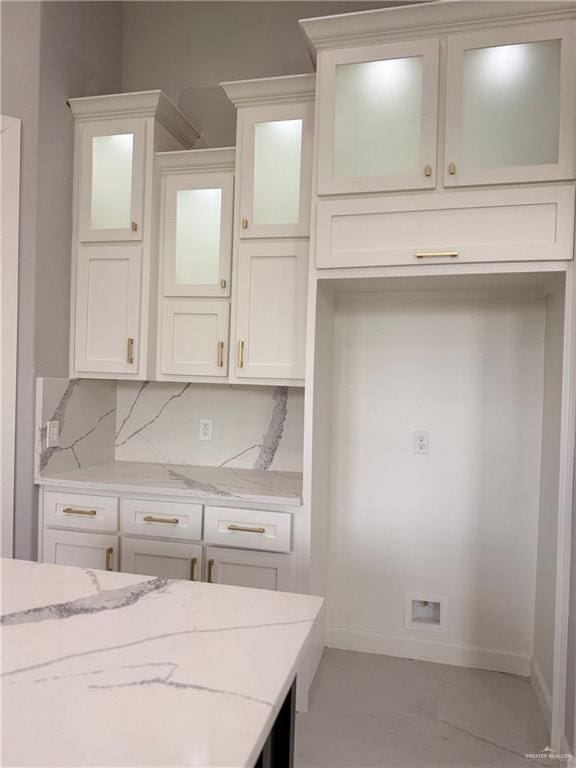 kitchen with backsplash, white cabinetry, and light stone counters