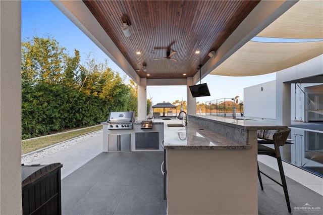 view of patio with an outdoor kitchen, area for grilling, sink, ceiling fan, and a gazebo