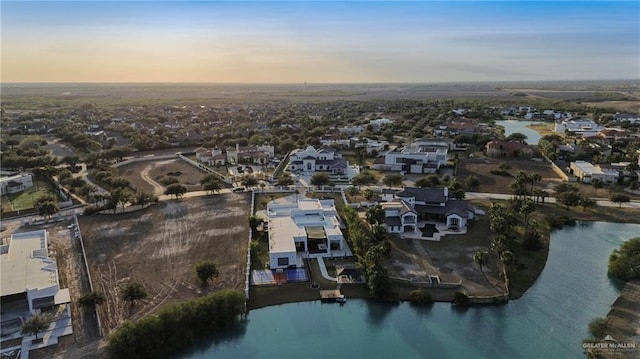 aerial view at dusk featuring a water view