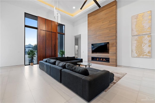 living room with light tile patterned flooring, a large fireplace, a tray ceiling, and a towering ceiling