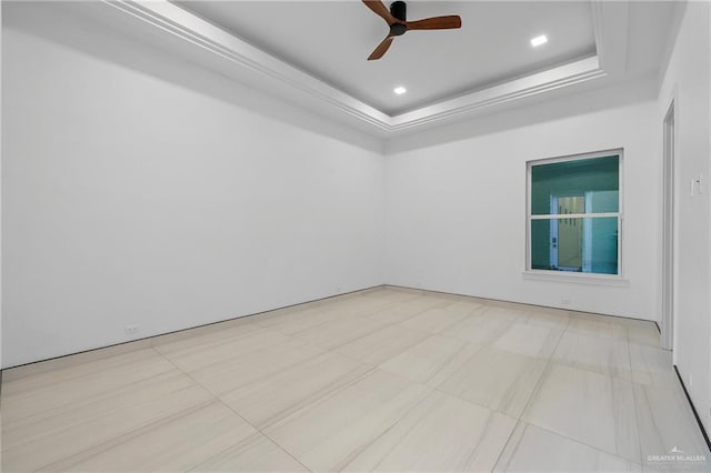 empty room with ceiling fan and a tray ceiling