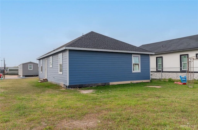 view of home's exterior with a yard, roof with shingles, and fence