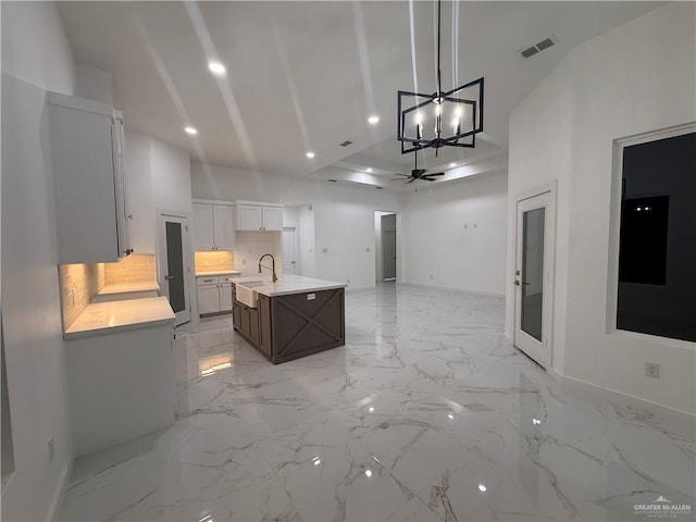 kitchen with light countertops, a chandelier, backsplash, a sink, and open floor plan