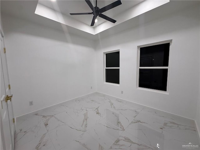 unfurnished room with baseboards, marble look tiles, and a ceiling fan