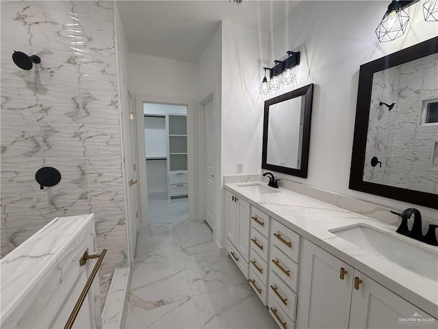 full bathroom featuring marble finish flooring, tiled shower, a spacious closet, and double vanity