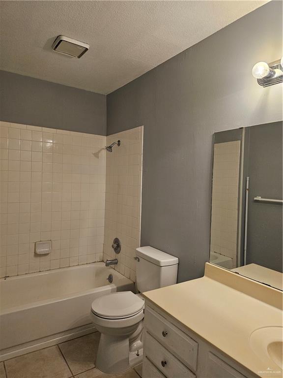 full bathroom with vanity, tile patterned flooring, a textured ceiling, and tiled shower / bath combo