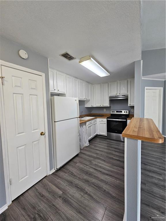 kitchen featuring wooden counters, white fridge, stainless steel electric stove, dark hardwood / wood-style flooring, and white cabinetry