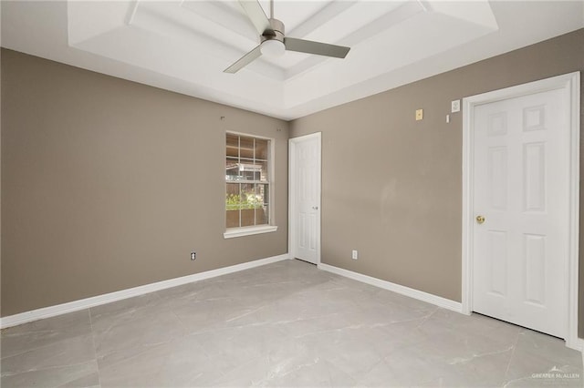 empty room featuring a raised ceiling and ceiling fan