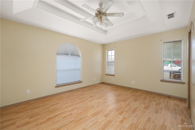 unfurnished room featuring ceiling fan, light hardwood / wood-style floors, and a tray ceiling