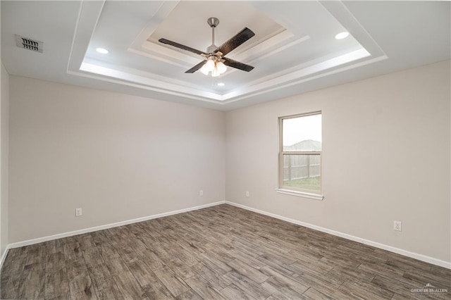 unfurnished room featuring baseboards, visible vents, a raised ceiling, and wood finished floors