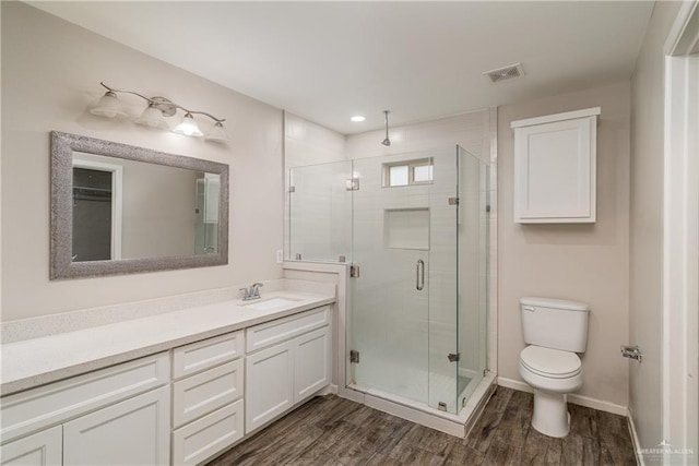 bathroom featuring toilet, wood finished floors, visible vents, vanity, and a stall shower