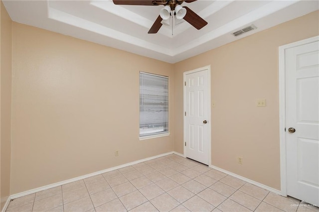 tiled spare room with a tray ceiling and ceiling fan