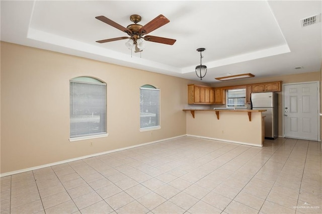 unfurnished living room featuring ceiling fan, a raised ceiling, and light tile patterned floors