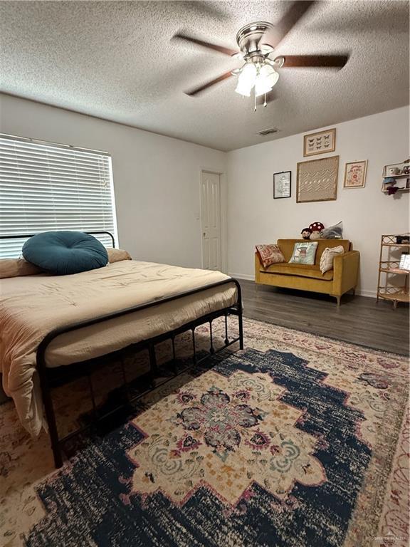 1341 Kokopelli Dr, Edinburg, TX 78541 - bedroom with a textured ceiling, baseboards, wood finished floors, and a ceiling fan