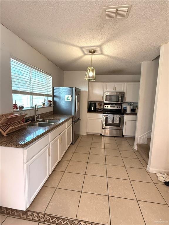 1341 Kokopelli Dr, Edinburg, TX 78541 - kitchen with stainless steel appliances, a sink, dark countertops, white cabinetry, and a textured ceiling