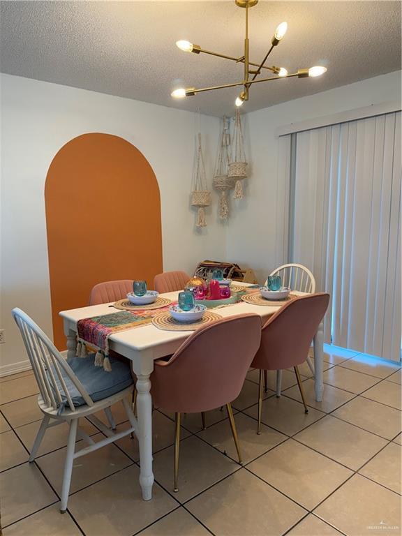 1341 Kokopelli Dr, Edinburg, TX 78541 - dining room with a textured ceiling, a chandelier, light tile patterned floors, and arched walkways