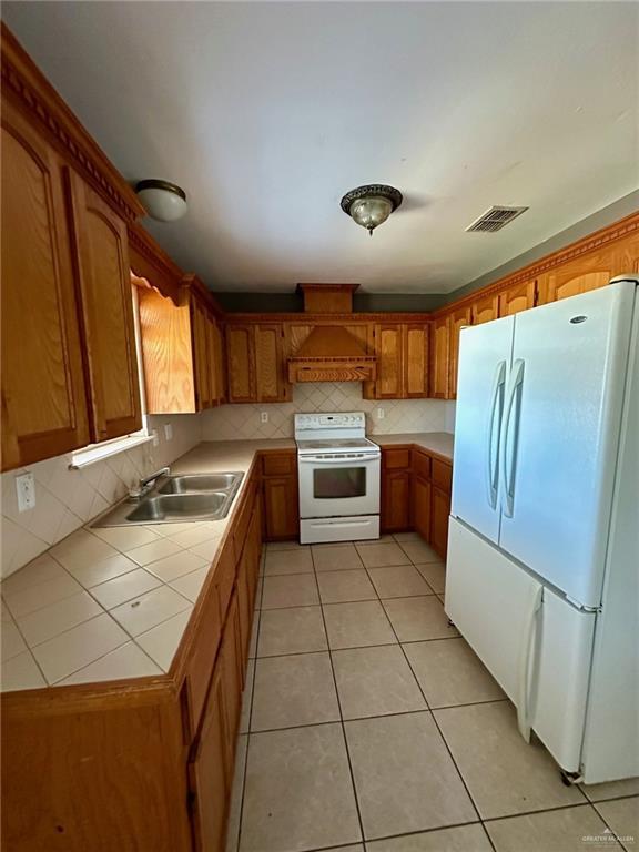 kitchen featuring tile countertops, light tile patterned floors, white appliances, visible vents, and decorative backsplash