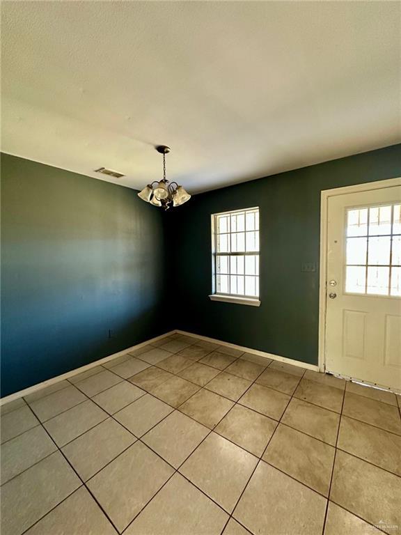 interior space featuring a chandelier, visible vents, baseboards, and light tile patterned floors