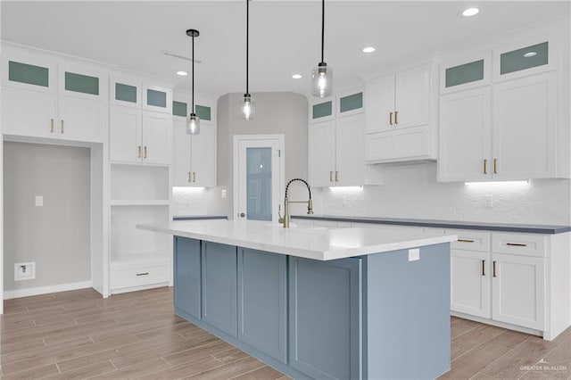 2427 Summer Breeze St, Mission, TX 78572 - kitchen featuring light wood-style floors, a center island with sink, backsplash, white cabinets, and recessed lighting