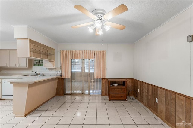 kitchen featuring wood walls, kitchen peninsula, ceiling fan, dishwasher, and sink