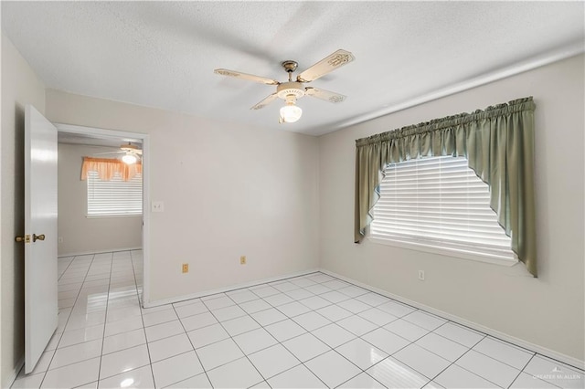 empty room featuring a textured ceiling, ceiling fan, and light tile patterned floors