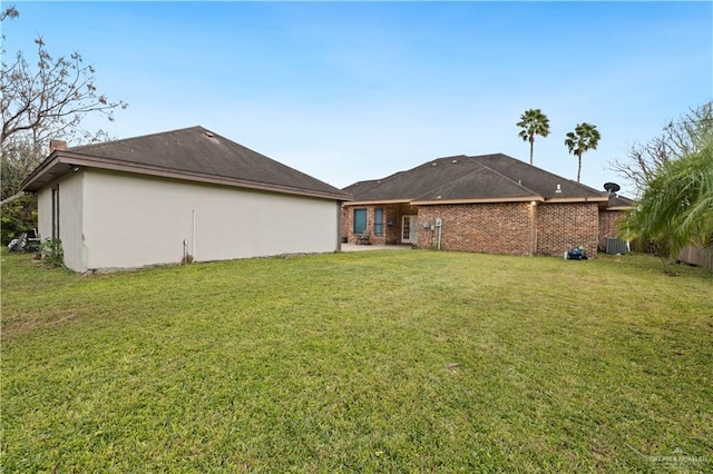 rear view of house featuring central AC unit and a yard