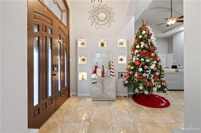 foyer entrance featuring ceiling fan and a towering ceiling