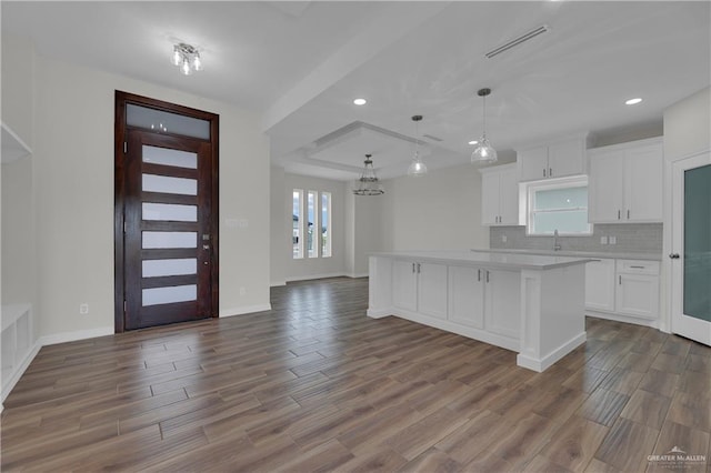 kitchen featuring white cabinetry, tasteful backsplash, pendant lighting, a kitchen island, and hardwood / wood-style flooring