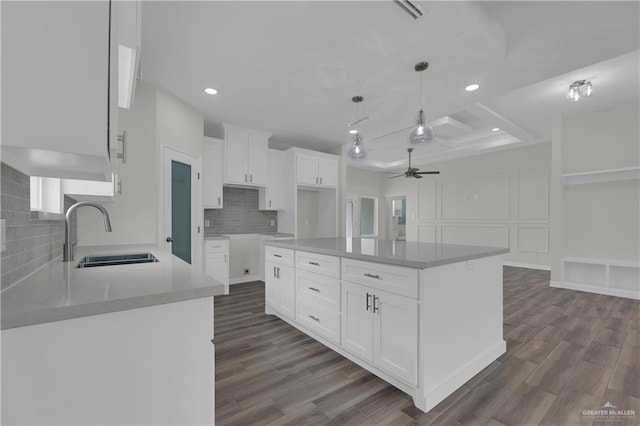 kitchen with white cabinetry, sink, a center island, and dark wood-type flooring