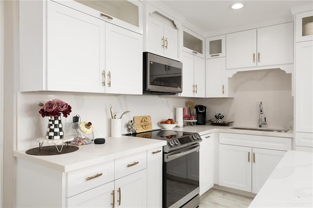 kitchen featuring range with electric cooktop, a sink, stainless steel microwave, white cabinetry, and light countertops