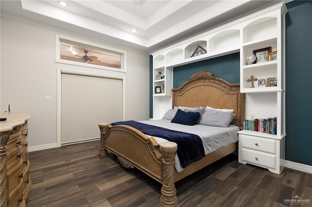 bedroom with dark wood finished floors, baseboards, and a tray ceiling