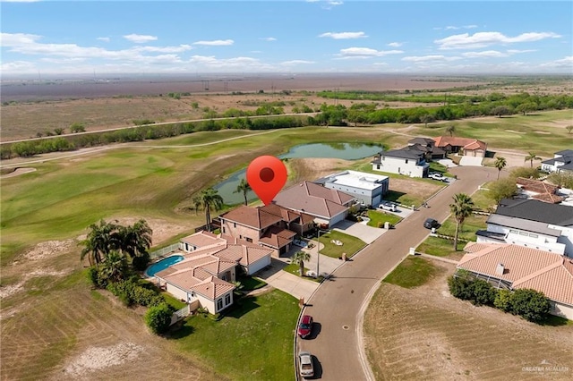 drone / aerial view featuring a residential view, view of golf course, and a water view