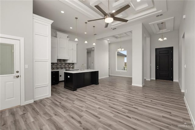 kitchen featuring light countertops, tasteful backsplash, open floor plan, visible vents, and white cabinets