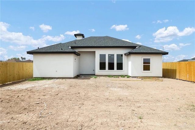 back of property featuring stucco siding, a shingled roof, and a fenced backyard
