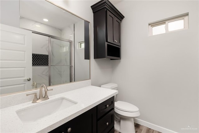 bathroom featuring baseboards, toilet, wood finished floors, vanity, and a stall shower