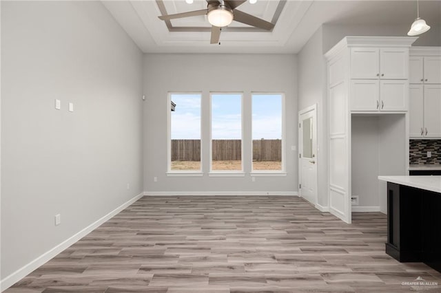 kitchen featuring white cabinetry, a raised ceiling, baseboards, and ceiling fan