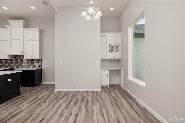 kitchen with baseboards, white cabinetry, light countertops, and backsplash