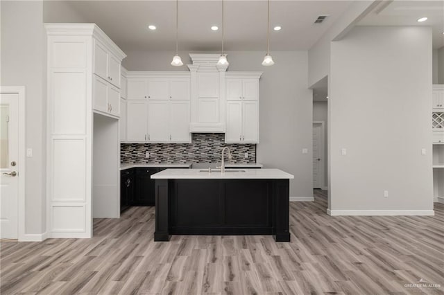 kitchen with visible vents, light countertops, backsplash, and a sink
