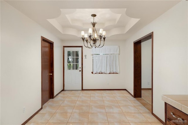 interior space with light tile patterned flooring, a raised ceiling, and a chandelier