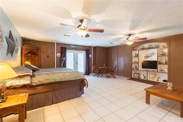 bedroom with ceiling fan, light tile patterned flooring, and a textured ceiling