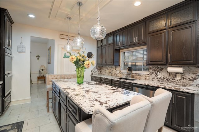 kitchen featuring dark brown cabinetry, sink, hanging light fixtures, a kitchen breakfast bar, and backsplash