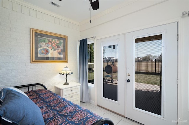 bedroom featuring french doors, ornamental molding, brick wall, and light tile patterned floors