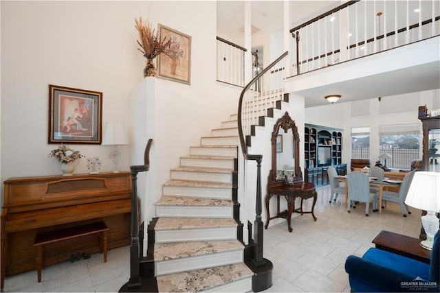 stairs with tile patterned flooring and a towering ceiling