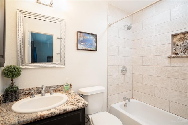 full bathroom with tiled shower / bath, vanity, and toilet