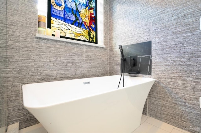 bathroom featuring tile patterned flooring, tile walls, and a washtub