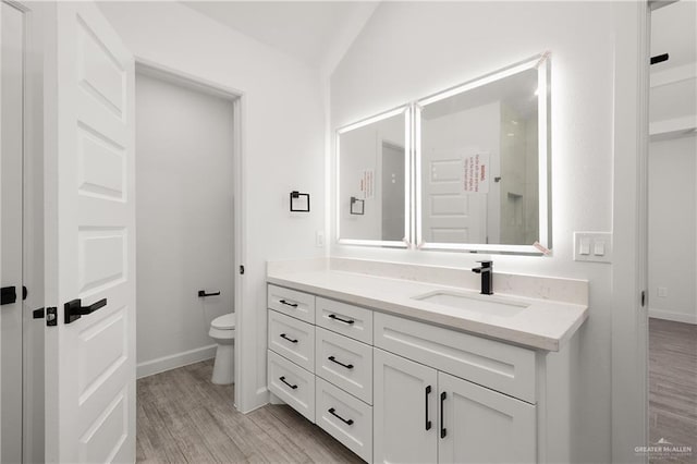 bathroom with hardwood / wood-style floors, vanity, lofted ceiling, and toilet