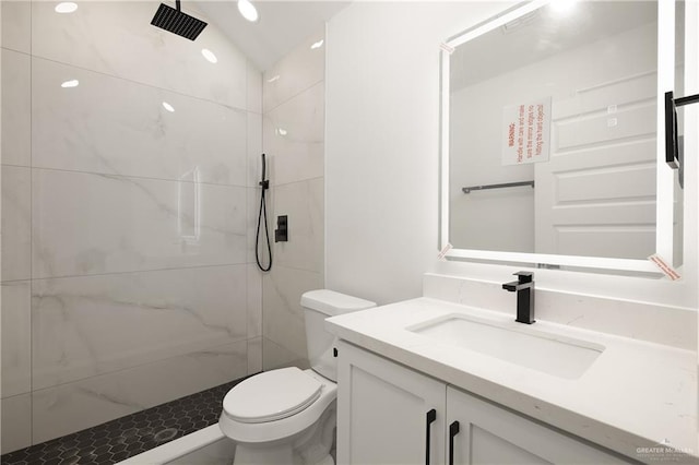 bathroom featuring toilet, vanity, tiled shower, and vaulted ceiling