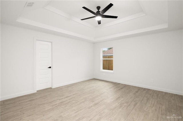 spare room featuring a tray ceiling, ceiling fan, and light hardwood / wood-style flooring