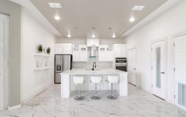 3011 E Ebano Ave, Hidalgo, TX 78557 - kitchen with stainless steel appliances, a kitchen island with sink, white cabinets, light countertops, and a breakfast bar