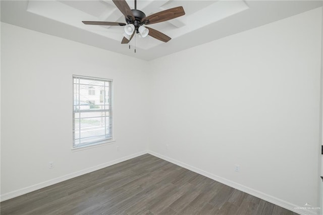 unfurnished room with dark wood-type flooring, a raised ceiling, baseboards, and a ceiling fan